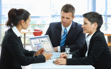 Photo of a businesswoman showing clients a computer program